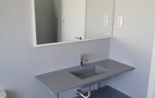 Encimera de baño con seno incorporado de 120x46 en color gris plomo colocada volada sobre soportes.